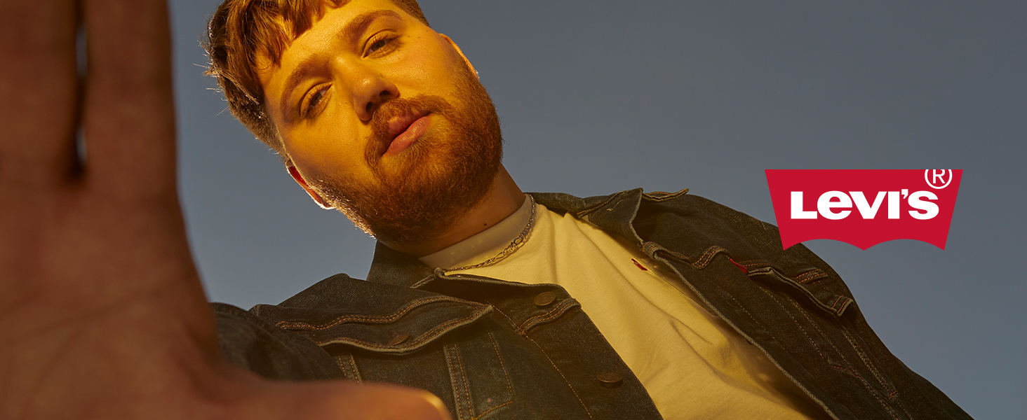 man wearing trucker jacket looking down and straight into camera